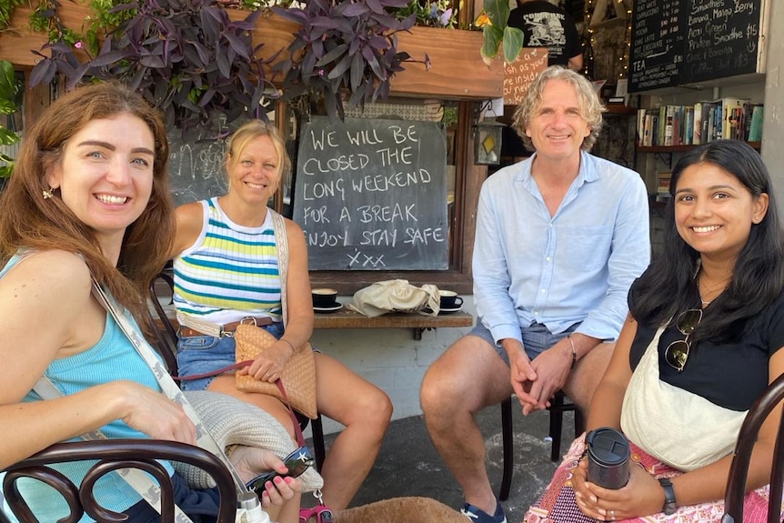 Four people looking at the camera and smiling while sitting outdoors at a Sydney cafe